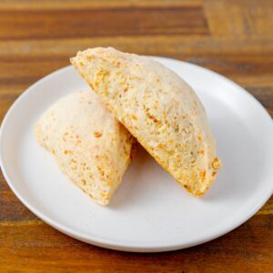 Two cheddar scones on a plate. These delicious scones are available at Simply Baked Catering Inc. in Winchester, Ontario.
